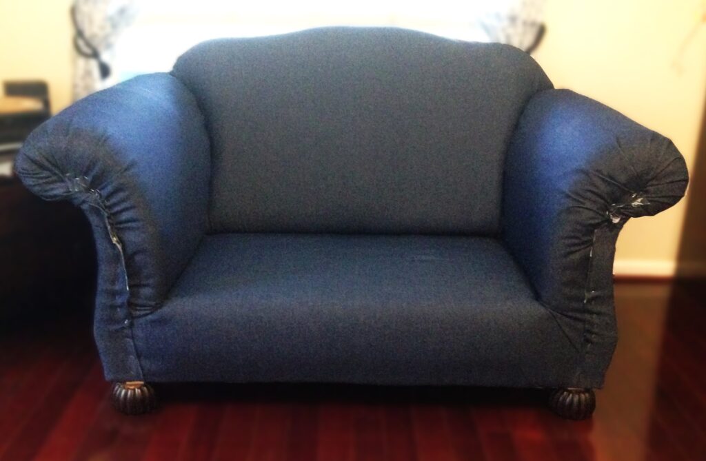 loveseat covered with denim and without wood trim applied.